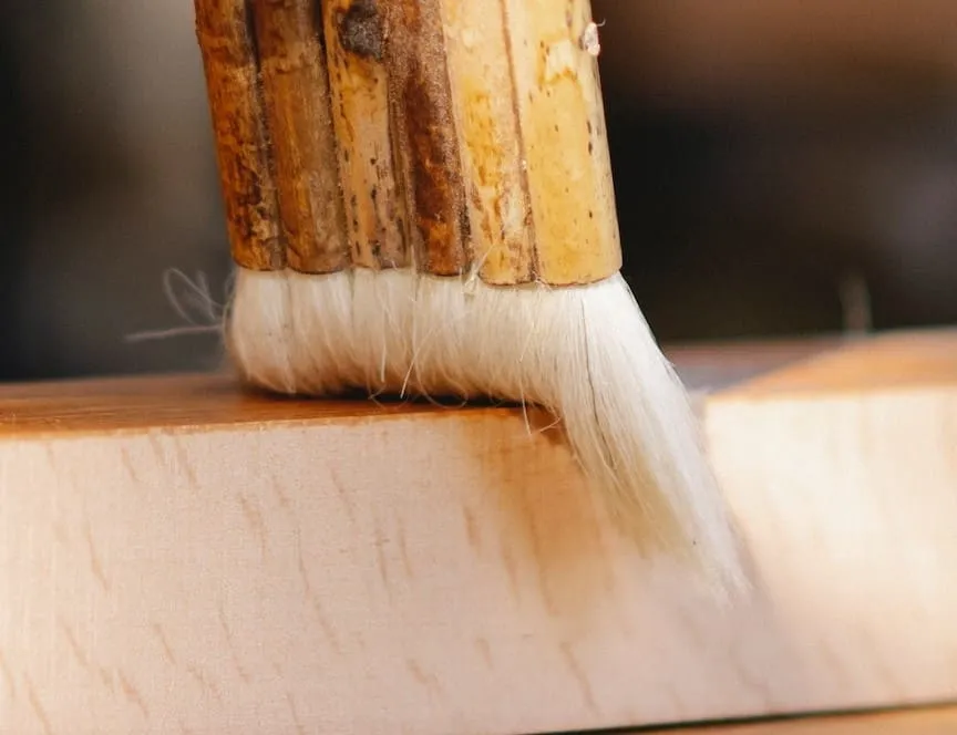 Close-up of a brush applying paint to wood, illustrating the type of paint used for beehives